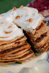 A mouthwatering close-up of an Argentine dessert cake layered with rich dulce de leche and crisp pastry, topped with a toasted meringue. The decadent layers are revealed in a slice