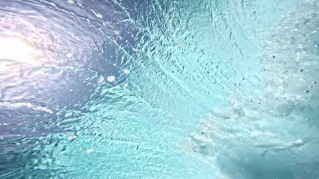 Underwater view of tube wave breaking over coral reef with spinning vortex. powerful nature, strong wave. Abstract bubbles texture, pattern, slow motion 4k.