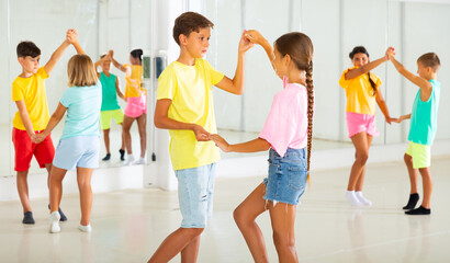 Fototapeta premium Kids in pairs exercising salsa moves together during group dance class.