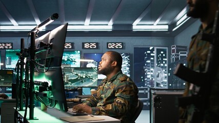 Army expert working in governmental facility operating surveillance tech, evaluating target data. Soldier doing job in HQ base of operations, engage enemy forces, camera B