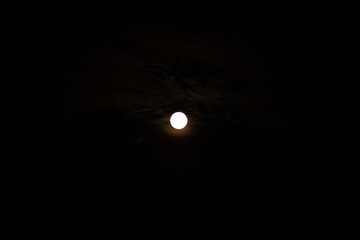 There is a full moon in the night sky, a full moon on a dark background.