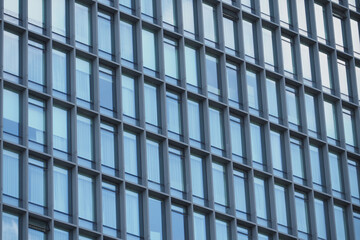 A modern office building facade with large glass windows that reflect its surroundings