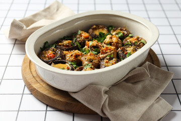 Stuffed mushrooms in baking tray on board and towel on light background