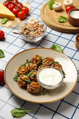 Stuffed mushrooms on plate, sauce and ingredients on light background