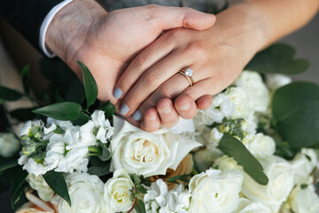 Closeup of bride and grooms hands on flowers.