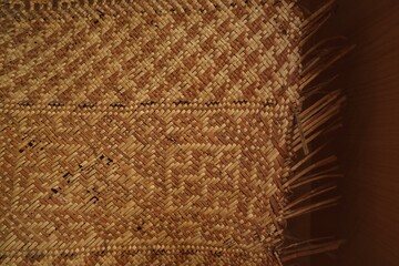The background and texture of the woven pandan mats are starting to have holes due to age.