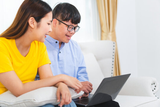 A group of friends using laptop doing a video call in living room, Young man and woman sitting on sofa and using a laptop