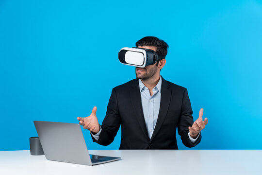 Skilled business man looking at data analysis while sitting at table with laptop and wearing VR glasses. Project manager working by using virtual reality system or connecting at metaverse. Deviation.