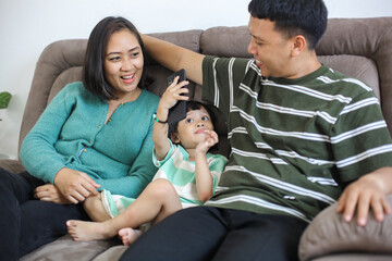 Happy Asian Family Having Fun Together Smiling Sitting on Sofa at Home