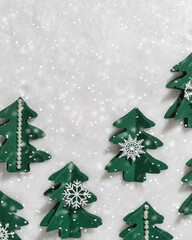 Trend pattern of Green Christmas trees cut out of craft paper on white fur, snowing, happy holiday concept. Diy green tree firs decorated snowflake, pearls. Minimal top view, Creative still life