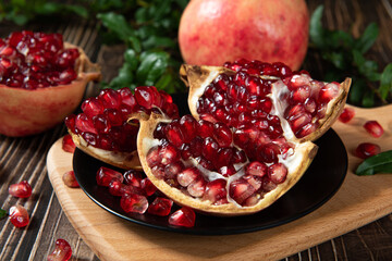 open pomegranates, and pomegranate seeds on wooden table.