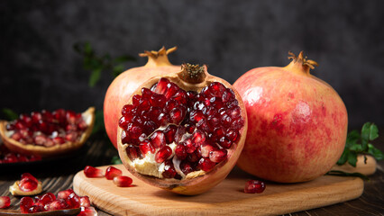 open pomegranates, and pomegranate seeds on wooden table.