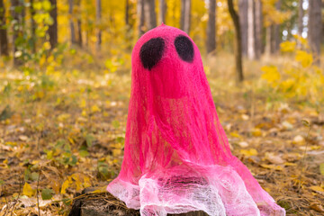Creative handmade Halloween holiday decoration. pink ghost in autumn leaves forest. Zero waste homemade decor. Mystic place supernatural 