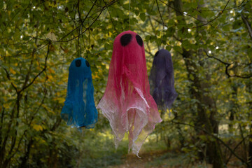 Halloween holiday concept. Handmade colorful ghosts made from bandages and glue flying in autumn...