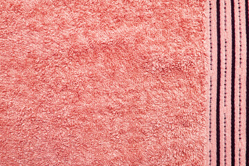 Fototapeta premium Close-up texture of a pink towel with a detailed look at the soft fabric and the subtle stripes along the edge