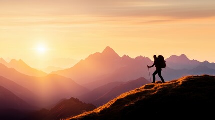 Fototapeta premium A lone hiker silhouetted against a majestic mountain range bathed in golden sunset light.