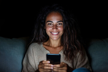 Smiling Woman Using Mobile Phone in the Dark