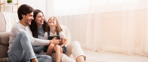 Family Love. Playful Parents Tickling Their Little Daughter, Having Fun Together At Home In Living...