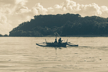 Obraz premium As the mountains stand tall in the port, the fishermen's boat sets sail.