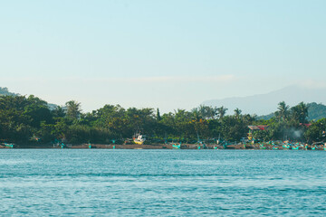 As the mountains stand tall in the port, the fishermen's boat sets sail.