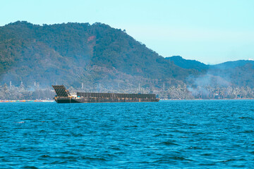 Obraz premium As the mountains stand tall in the port, the fishermen's boat sets sail.