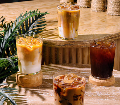 Four iced coffee drinks sitting on a cafe table in the sun