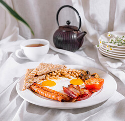 Full english breakfast with crispy bacon and sunny side up eggs being served for breakfast