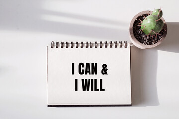 White notebook with I Can and I Will in bold black letters, open on a white surface.