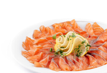 Sliced salmon fillet decorated with lemon and parsley on white plate