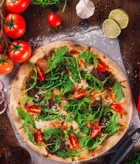 Freshly baked pizza lying on table with various ingredients around