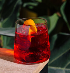Red cocktail standing on table in tropical setting