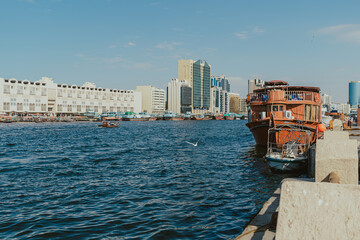 Obraz premium Dubai, UAE - January 6, 2020: Scenic view of boats on Dubai Creek with modern buildings in the background