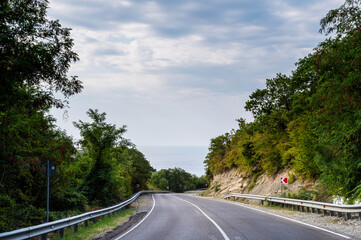 Fototapeta premium Highway road with curve through forest under dramatic sky