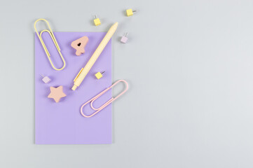 Top view of purple notebook on grey background. Paperclips, pen, number, shape and pins. School, office wallpaper. Flat lay, copy space.