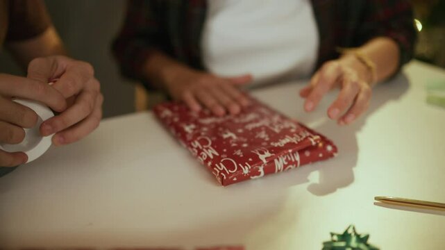 Hands skillfully wrapping christmas gift with festive paper and tape