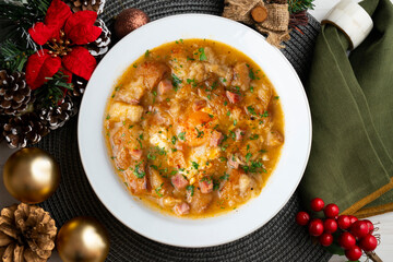Castilian soup with vegetables, bread croutons and egg. Top view table with Christmas decorations.