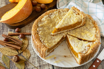Fall traditional pumpkin pie with cinnamon on a rustic wooden background.