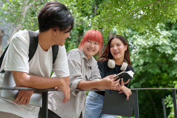 Bright Asian College Student Cheerful people use laptops and tablets to study with a group of classmates. Study outside in a fun way with good friends and social media. Concept of online education.