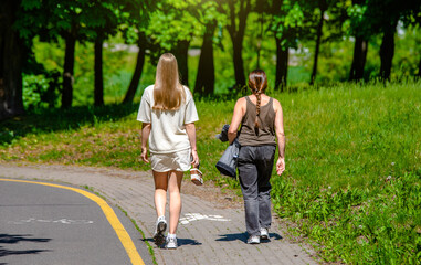 Two girlfriends walk along a path in the Park
