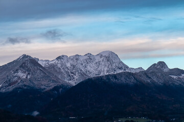Scenic view of snow-capped mountain peak Mittagskogel (Kepa) in Karawanks at sunrise seen from Rosental, Carinthia, Austria. Cloud covered alpine landscape. Peaceful scene in Austrian Alps in winter