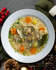 Rice, vegetable and clam soup, traditional Spanish tapa. Top view table with Christmas decorations.