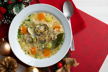 Rice, vegetable and clam soup, traditional Spanish tapa. Top view table with Christmas decorations.