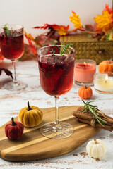 Autumn spiced cocktail with wine on a rustic holiday table. Homemade seasonal drink Sangria for Halloween, Thanksgiving with cinnamon and rosemary. Decorative textile pumpkins and candles