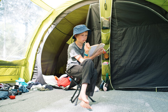 boy sat doing a crossword in a tent whilst camping in Sweden