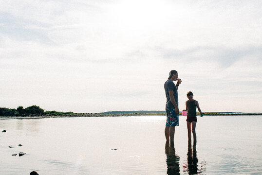 father on the beach with his daughter looking for crabs in the sea