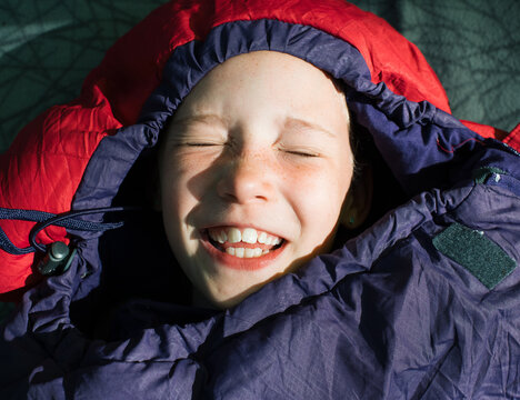 child in a sleeping bag zipped up to the top whilst camping