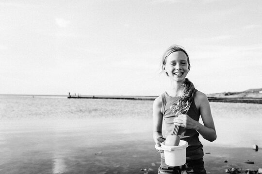 child happily playing in the sea at the beach with a bucket and spade