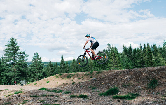 man doing a jump on his bike at a bike park in the mountains