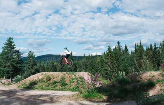 man doing a jump whilst at a bike park in the mountain