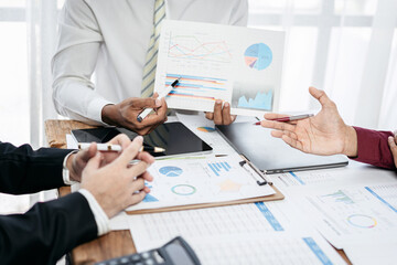 Three people are sitting at a table with a lot of papers and graphs